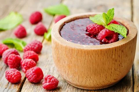 Raspberry jam on a dark wood background. the toning. selective focus Stock Photos