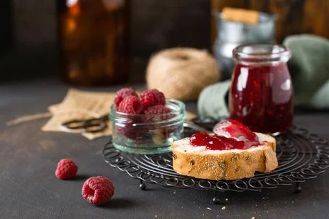 Raspberry jam in glass jar and sandwich with fresh raspberry berries on the o Stock Photos