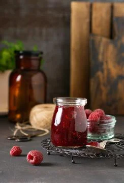 Raspberry jam in a glass jar with fresh raspberry berries on the old retro ba Stock Photos