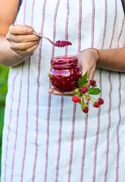 Raspberry jam in the hands of a woman. Selective focus. Stock Photos