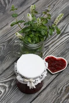 Raspberry jam in jars and a saucer. On pine planks painted black and white. N 스톡 사진