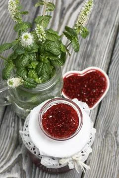 Raspberry jam in jars and a saucer. On pine planks painted black and white. N Stock Photos