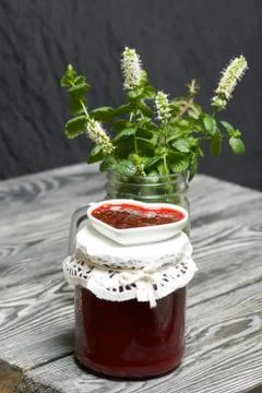 Raspberry jam in jars and a saucer. On pine planks painted black and white. N Stock Photos