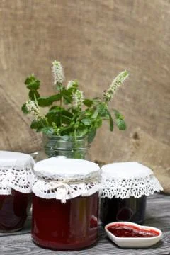 Raspberry jam in jars and a saucer. On pine planks painted black and white. N Foto stock