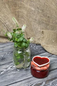 Raspberry jam in jars and a saucer. On pine planks painted black and white. N Stock Photos