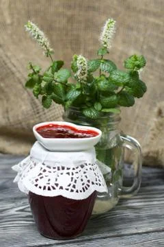Raspberry jam in jars and a saucer. On pine planks painted black and white. N Stock Photos