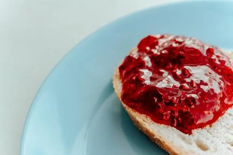 Raspberry jam on a piece of bread close up on a blue plate Stock Photos