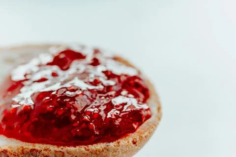 Raspberry jam on a piece of bread close up on a white background Stock Photos