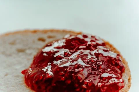 Raspberry jam on a piece of bread close up on a white background Stock Photos