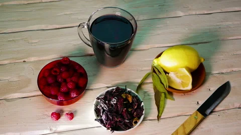 Raspberry lemon tea in a transparent mug on wooden boards. Fruit red tea Stock Footage 163771126