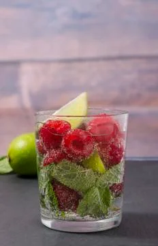 Raspberry lemonade with lime and mint in a glass. Stock Photos
