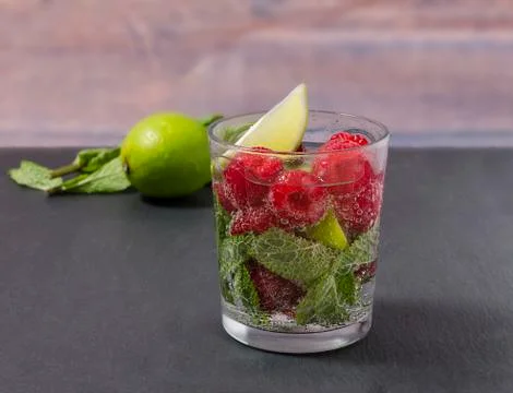 Raspberry lemonade with lime and mint in a glass. Stock Photos