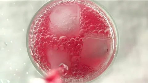 Raspberry lemonade is poured into a glass with ice on a light background Stock Footage 161177427
