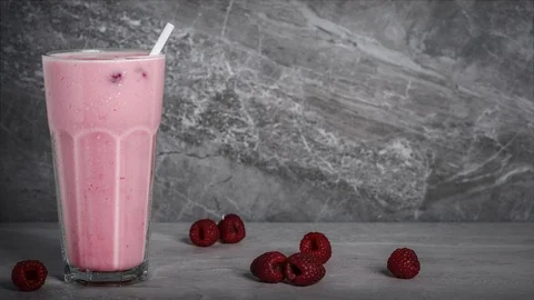 Raspberry milkshake or smoothie with scattered fresh washed organic raspberri Vídeo Stock 106359198