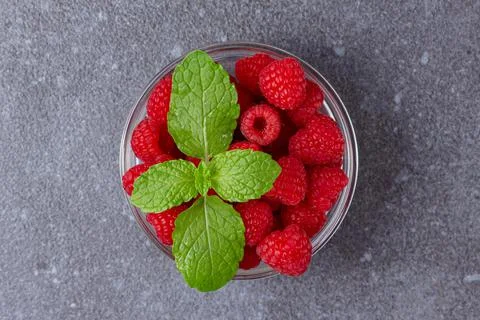 Raspberry with mint in bowl on dark background. Stock Photos