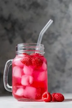 Raspberry refreshing lemonade in mason jar with glass straw, summer cold drink. Stock Photos