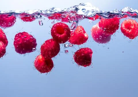 Raspberry splash in water Stock Photos