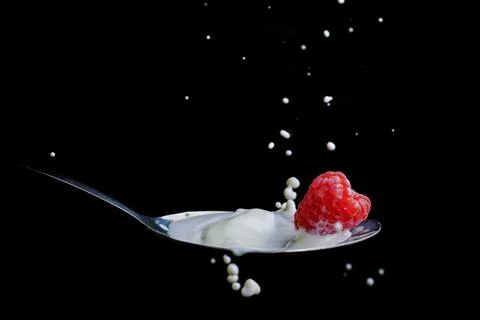 Raspberry splashing milk on a metallic spoon splash effect Stock Photos