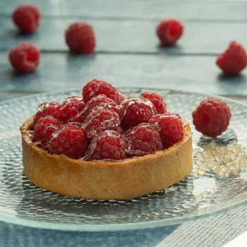 Raspberry tartlets served on a transparent plate with brown sugar. Glass of milk Stock Photos