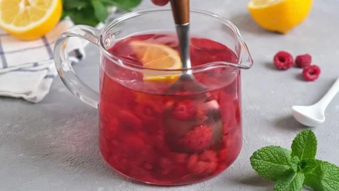 Raspberry tea with berries in glass teapot. Mixing raspberry tea with spoon Stock Footage 151162184