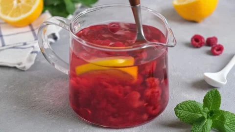Raspberry tea with berries in glass teapot. Mixing raspberry tea with spoon Stock Footage 153034685