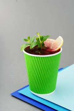 Raspberry tea in paper green cup on gray background. Mockup. Take away tea. Tea Stock Photos