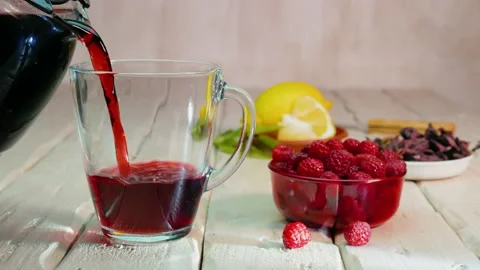 Raspberry tea poured into a transparent red tea cup on vintage wooden boards Stock Footage 163685678