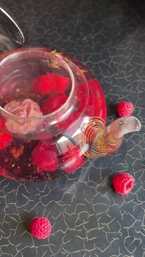 Raspberry tea with rose Hand preparing fresh flower tea in elegant glass teapot Stock Footage 317702051