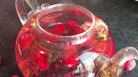 Raspberry tea with rose Hand preparing fresh flower tea in elegant glass teapot Stock Footage 317703445