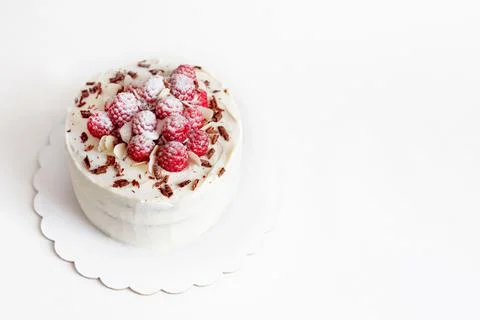 Raspberry white mastic cake decorated fresh berries on cake stand, white table. Stock Photos