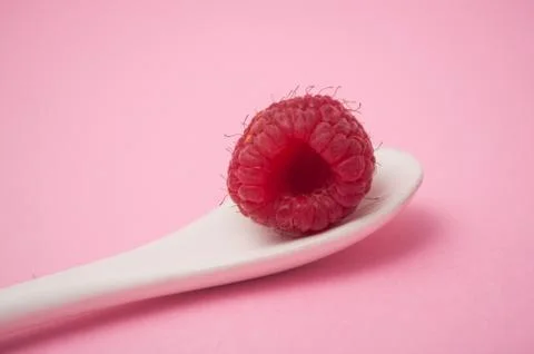 Raspberry in a white spoon on pink background Stock Photos