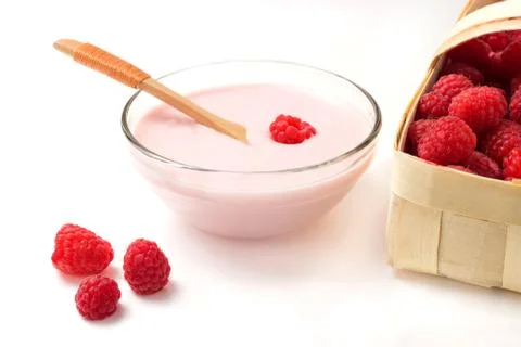 Raspberry yogurt in a glass cup with raspberry basket on a white background Foto stock
