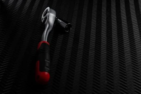 Ratchet wrench with socket attachment in use position on dark textured back.. Foto stock