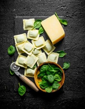Ravioli raw with Parmesan and spinach leaves. Stock Photos