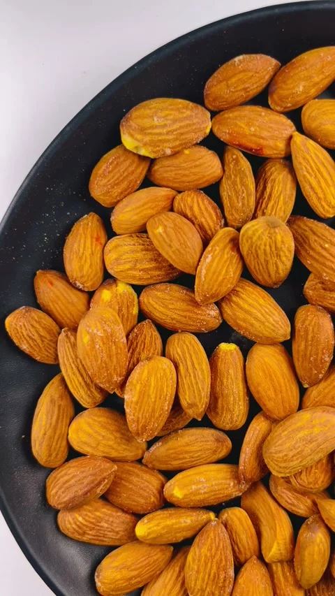 Raw almond nuts in black plate top view Stock Footage 336471535