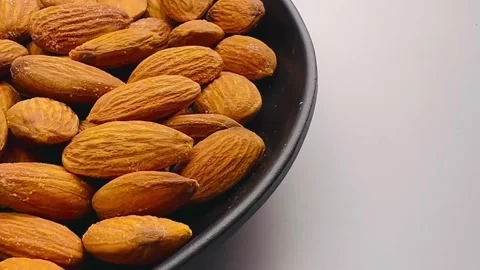 Raw almond nuts in black plate close up Stock Footage 336471540