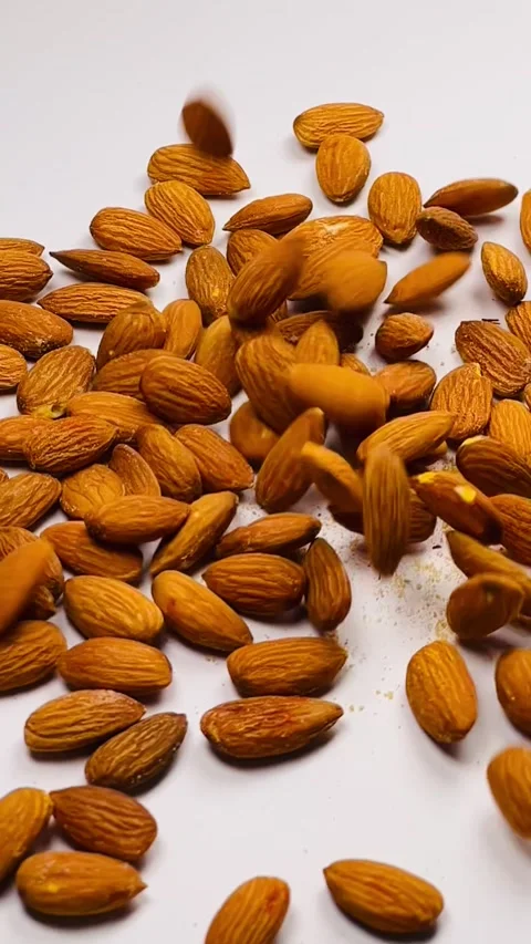 Raw almond nuts falling in slow motion on white background Stock Footage 336471531