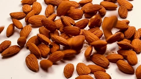Raw almond nuts falling in slow motion on white background Stock Footage 336471533