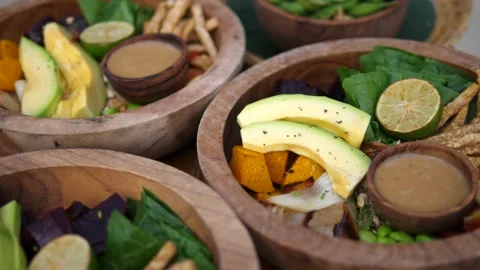 Raw and rustic plant based lunch. Vegetables, leaves and avocado served in Stock Footage 154639802
