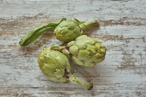 Raw artichoke on a rustic plank Stock Photos