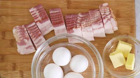 Raw bacon, and raw eggs close-up on a wooden background.  Video stock 238794137