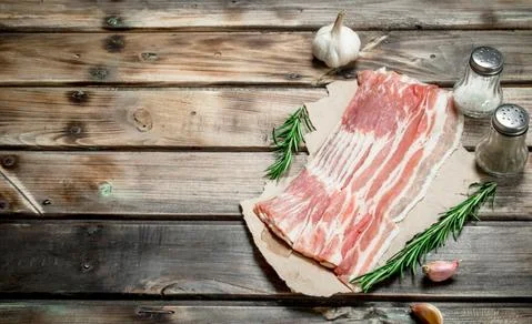 Raw bacon on paper. Stock Photos