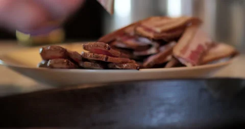 Raw bacon on plate ready to be cooked in cast iron skillet. Video stock 138332983