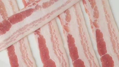 Raw bacon strips lying on white background 스톡 동영상 348307639