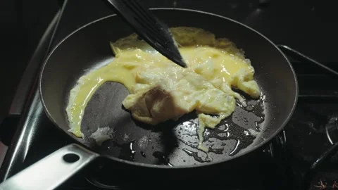 Raw beaten eggs being poured into hot pan Vídeo Stock 338306100