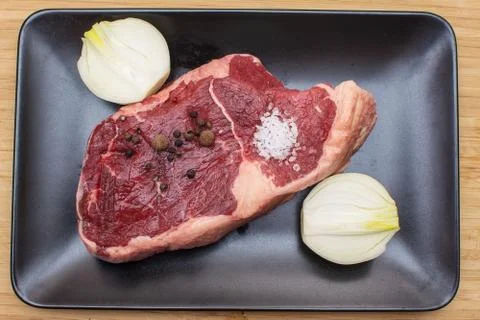 Raw beef on a black plate. Stock Photos
