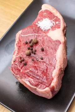 Raw beef on a black plate. Stock Photos