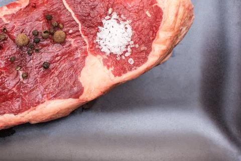 Raw beef on a black plate. Stock Photos