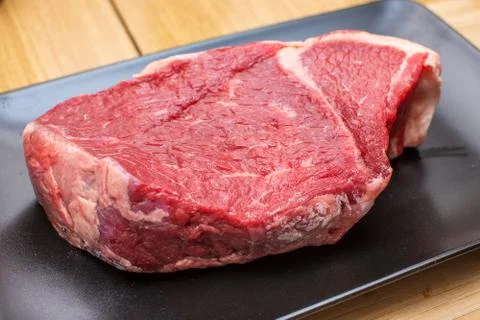 Raw beef on a black plate. Stock Photos