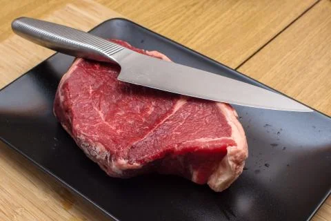 Raw beef on a black plate. Stock Photos